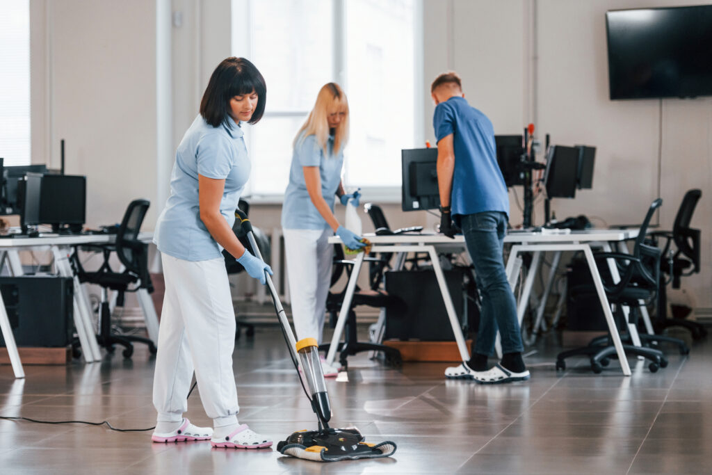 A team cleaning and vacuuming a commercial workspace.